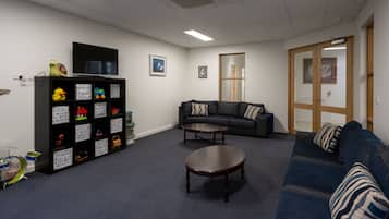 Relax in this cozy living space with a comfortable sofa, flat-screen TV, and shelving unit.