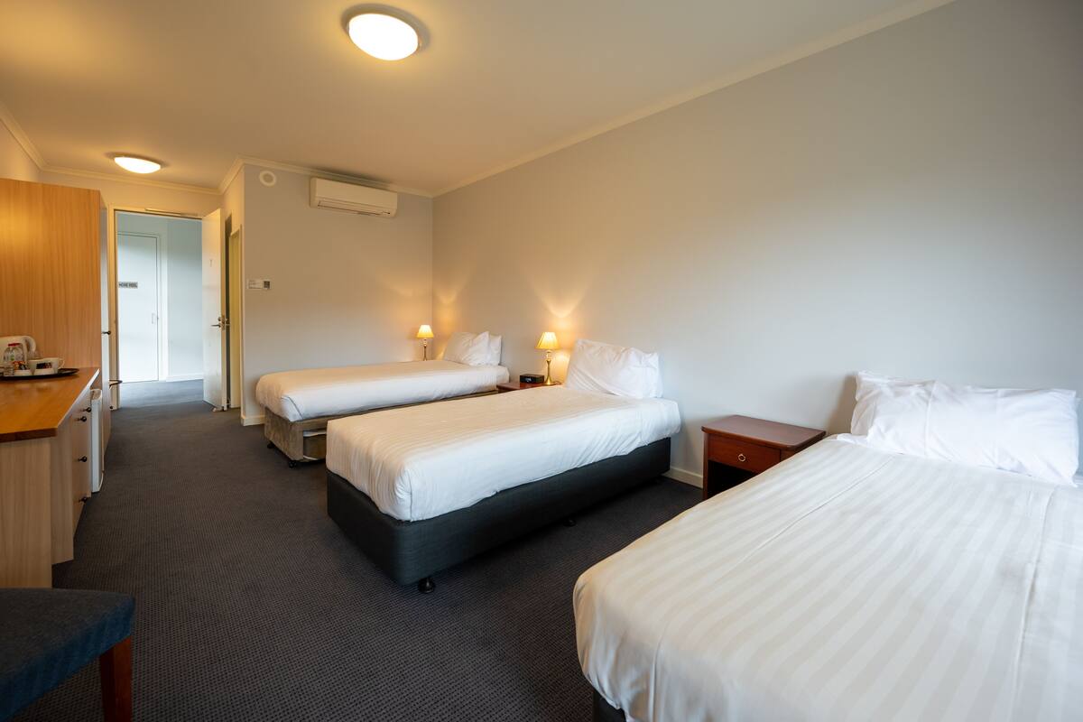 Ein Hotelzimmer mit zwei Einzelbetten, einem Schreibtisch und einem Kleiderschrank.