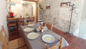 A dining area with a stone wall, wooden furniture, and a chandelier.