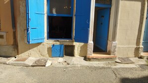 A building with blue shutters, a small window, and a door.