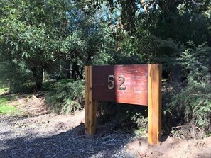 Ein Holzschild mit der Nummer 52, umgeben von dichtem Grün.