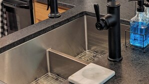 A kitchen with a stainless steel sink, a black faucet, and a soap dispenser on the countertop.