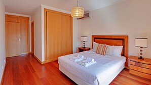 Ein ordentlich eingerichtetes Schlafzimmer mit einem großen Bett, einem Holzschrank, Nachttischen und einer Hängeleuchte.