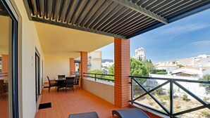 Ein Balkon mit Tisch und Stühlen, Blick auf die Stadt, und ein Gebäude im Hintergrund.
