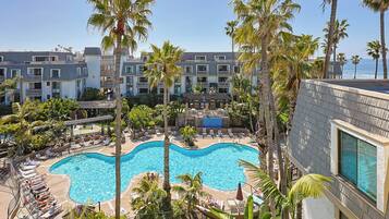 A resort with a large swimming pool surrounded by palm trees and lounge chairs.