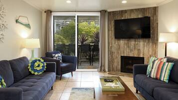 A living room with two sofas, a coffee table, a TV mounted on a wooden wall, and a fireplace.