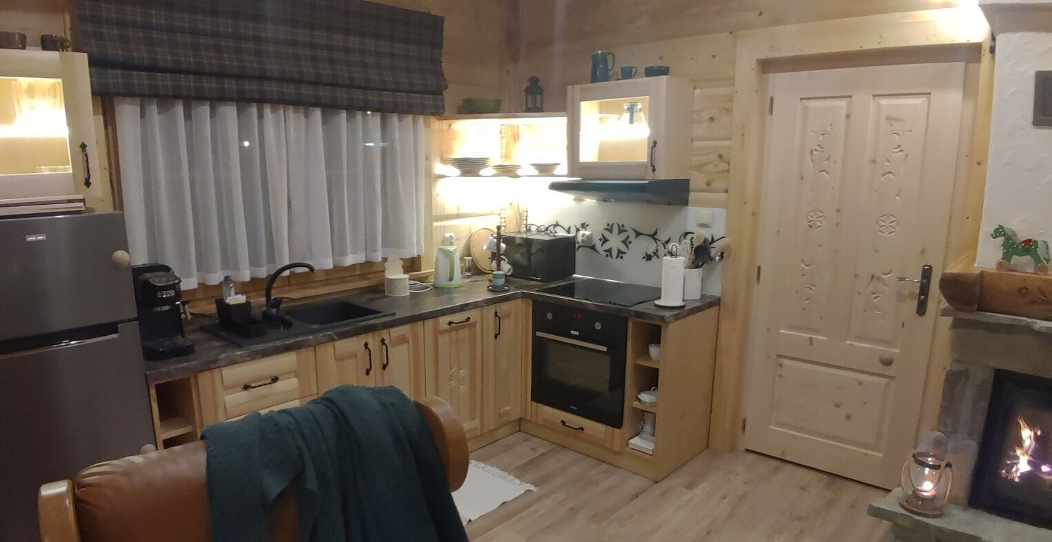 Una cocina acogedora con armarios de madera, estufa y comedor con mesa y sillas.