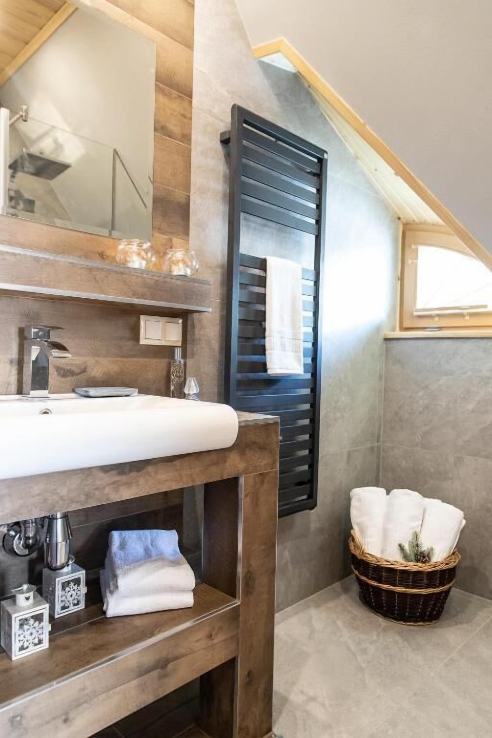 A modern bathroom with a wooden vanity, a large mirror, and a towel rack.