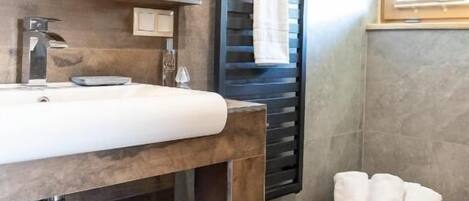A modern bathroom with a wooden vanity, a large mirror, and a towel rack.