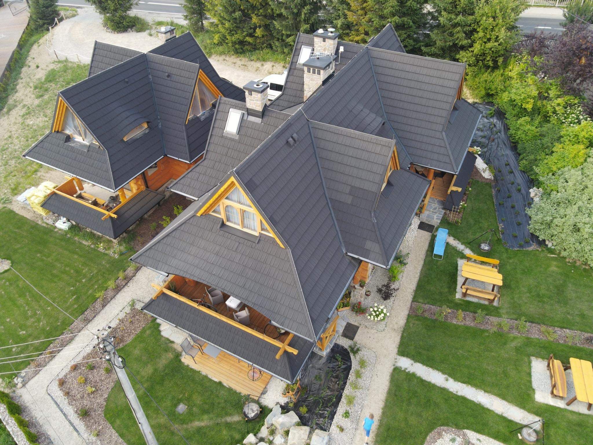 A multi-story house with a sloped roof, wooden deck, and a small garden area.