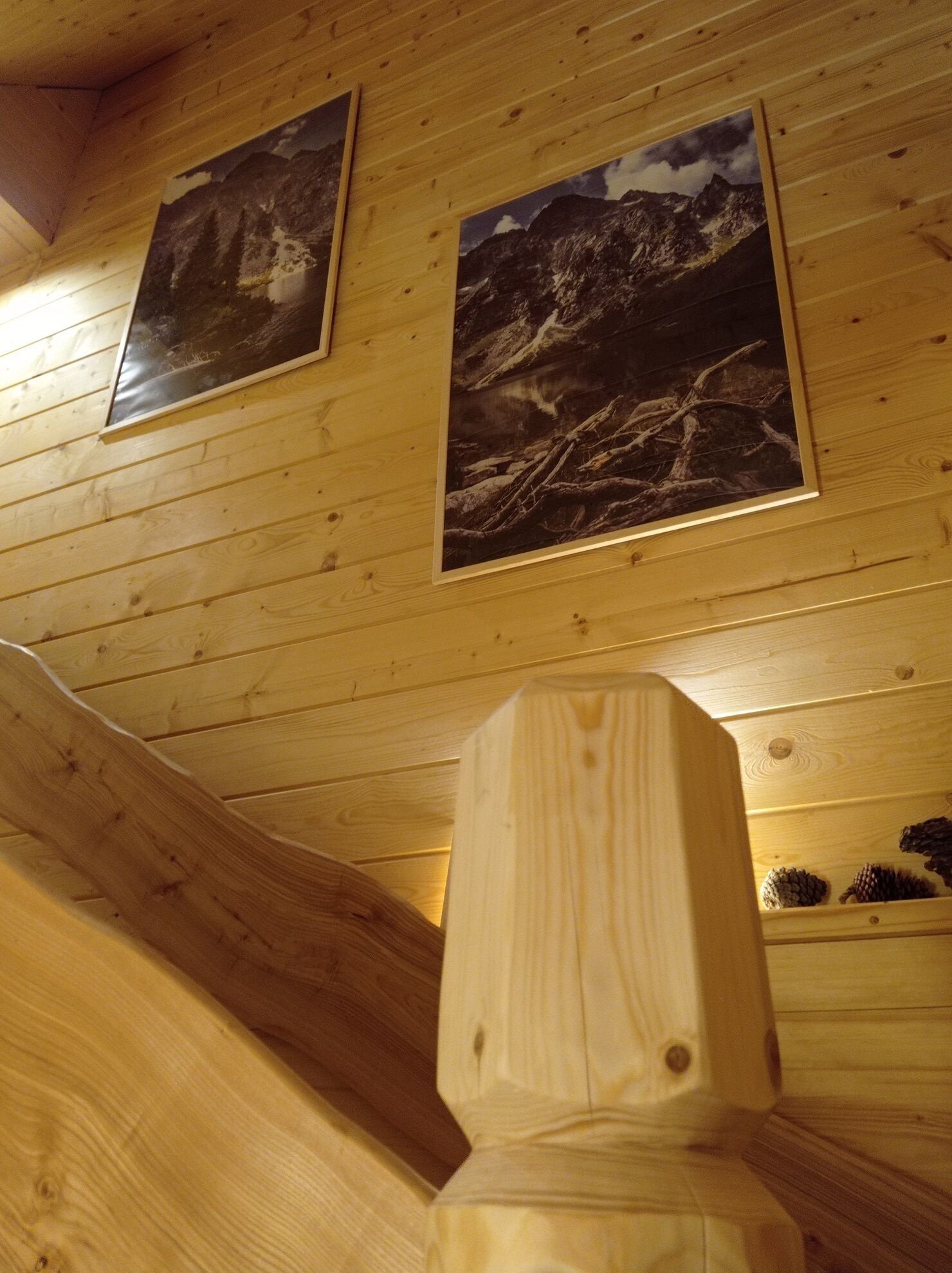 Eine Holztreppe mit Holzwurf und einer Wand mit zwei gerahmten Bildern von Bergen.