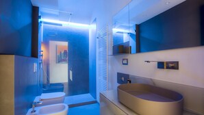 Ein modernes Badezimmer mit einem großen Spiegel, einer freistehenden Badewanne und einem wandmontierten Waschbecken.