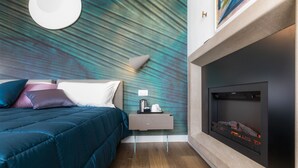 Ein modernes Schlafzimmer mit Bett, Nachttisch und Kamin.