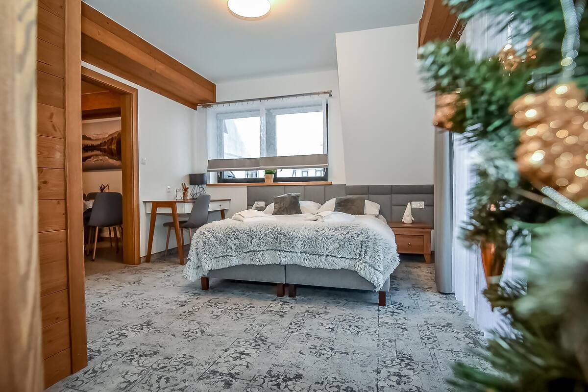Un dormitorio con cama, ventana, escritorio y silla.