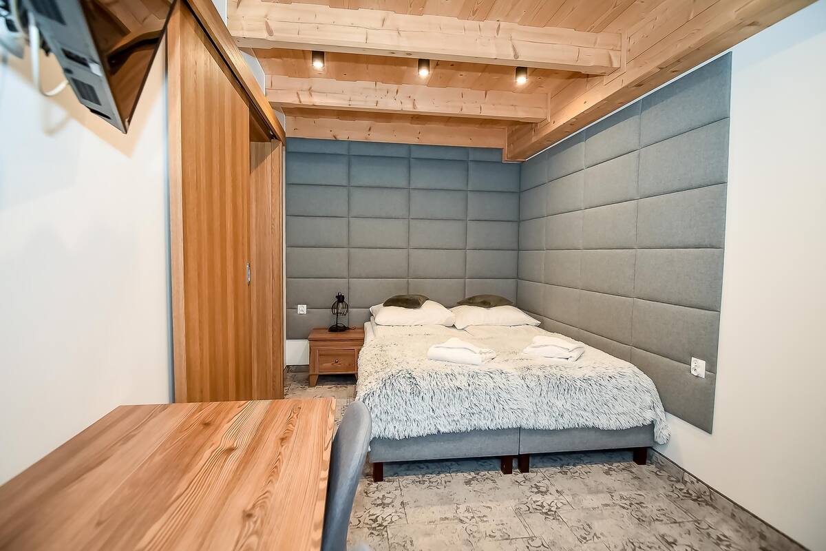 Un dormitorio con una cama, una mesita de noche de madera y una mesa.