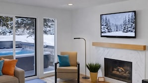 A modern living room with a sofa, a chair, a coffee table, a fireplace, and a large window overlooking a pool. - Open Floor 71 Vantage Family Condo by RedAwning (Park City)
