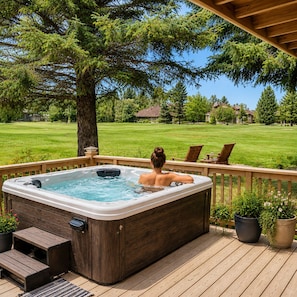 A hot tub on a wooden deck with a view of a grassy yard and houses.