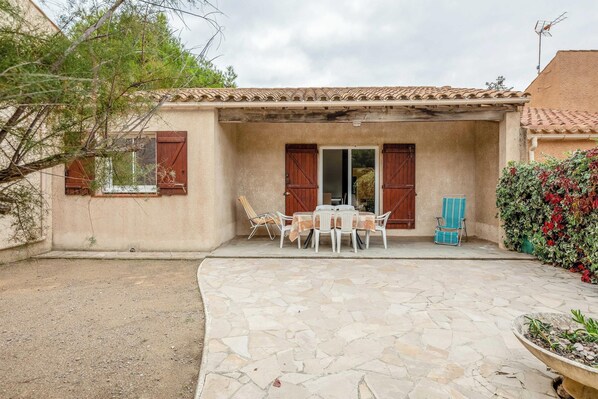 Un patio con piso de piedra, una mesa con sillas y una silla azul.