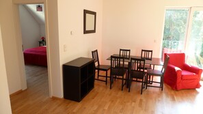 Cozy living space with a dining area, featuring a dining table and six chairs, a comfortable armchair, and a sleek entertainment unit.