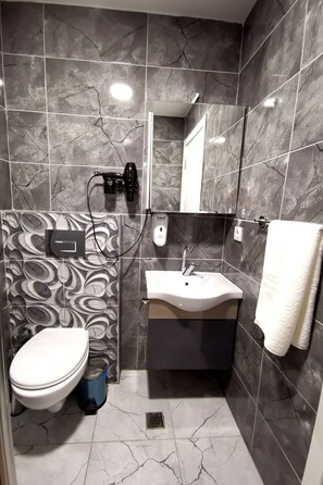 Une salle de bain avec des toilettes, un lavabo et un miroir.