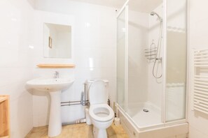 Een douche, handdoeken, zeep, toiletpapier