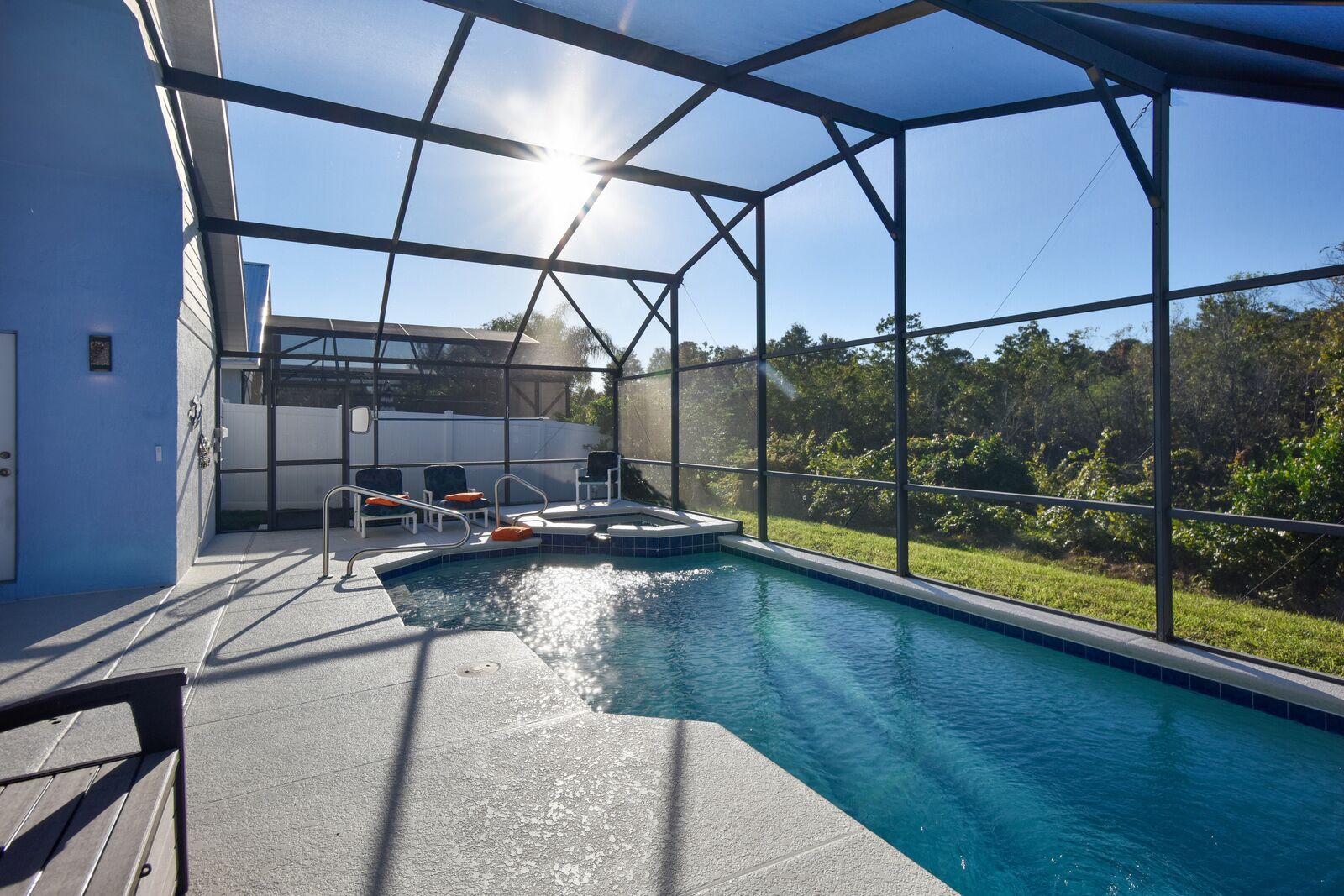 A swimming pool with a glass enclosure, a hot tub, and outdoor seating.