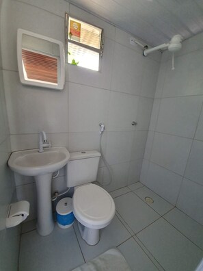 Une petite salle de bain propre, équipée de toilettes, d’un lavabo et d’une douche.
