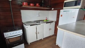 Une cuisine de taille réduite, équipée d’une cuisinière, d’un évier et d’un réfrigérateur.