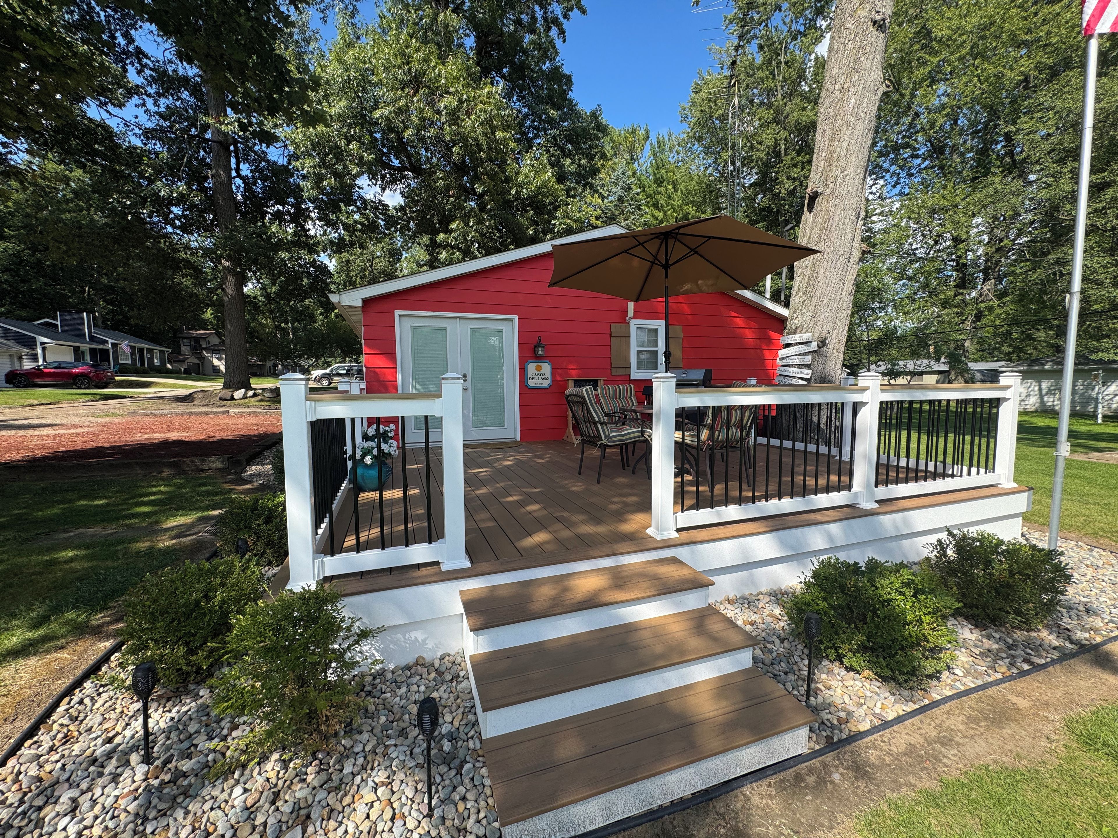Une maison rouge avec une terrasse, une porte blanche et un drapeau.