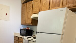 A kitchen with wooden cabinets, a white refrigerator, a microwave, and a stove. - Basics 90's Condo 906 Downtown Moses Lake (Moses Lake)