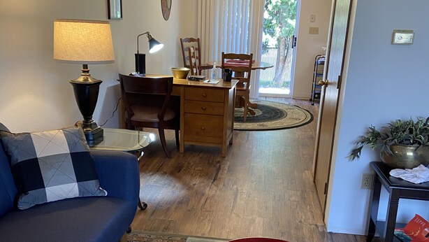 A living room with a blue sofa, a glass coffee table, and a dining area with wooden chairs and a table. - Basics 90's Condo 906 Downtown Moses Lake (Moses Lake)