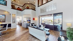 A spacious living area with a high ceiling, wooden flooring, a white sofa, and a dining area with a view of the outdoors. - 4 bdrm house close to restaurants, beach, attractions and quick boating access (Cape Coral)