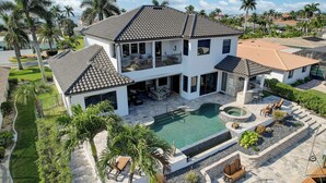 A two-story house with a swimming pool, outdoor seating, and palm trees. - 4 bdrm house close to restaurants, beach, attractions and quick boating access (Cape Coral)