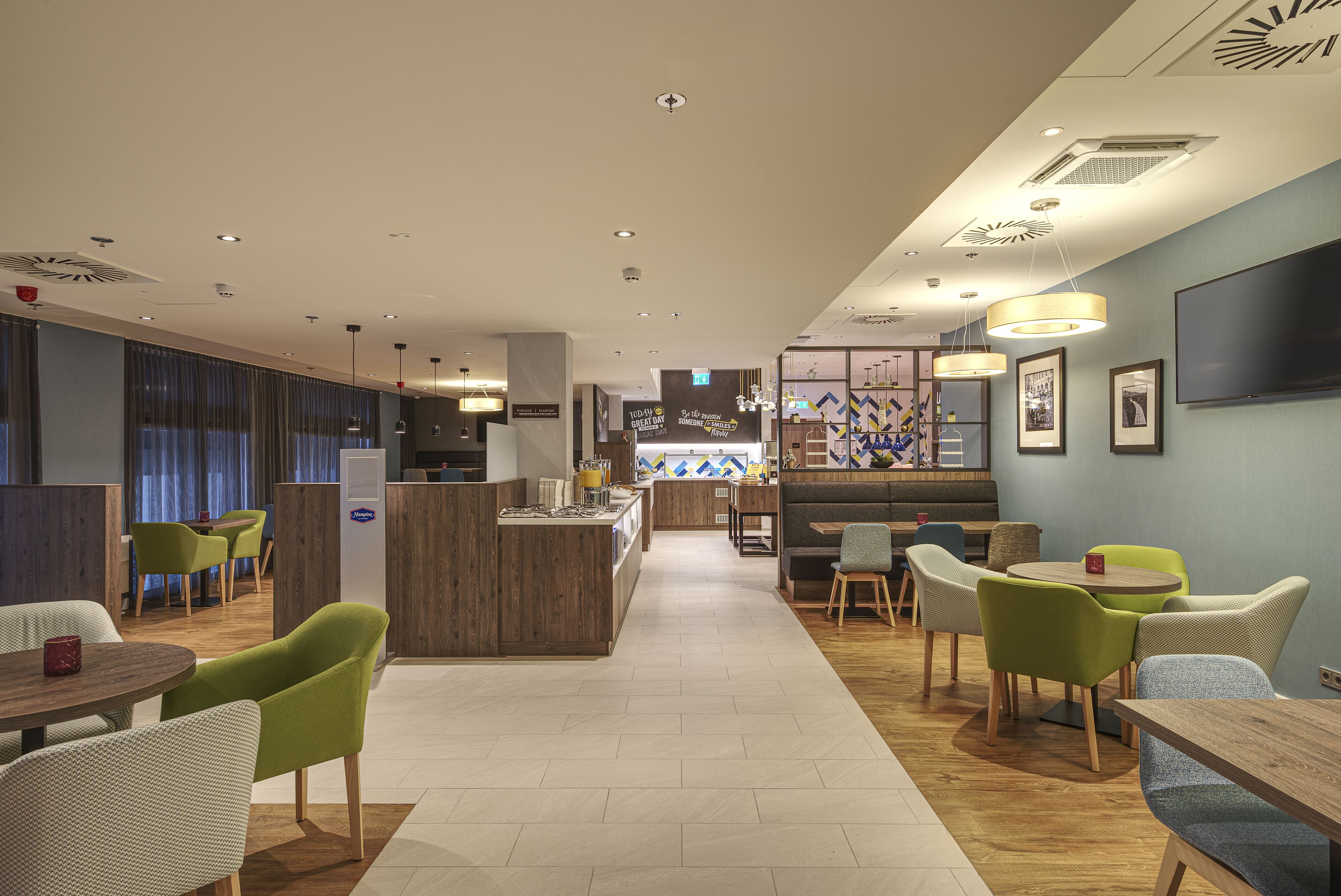 Un moderno vestíbulo de hotel con una zona de bar central, espacios de asiento y una recepción.