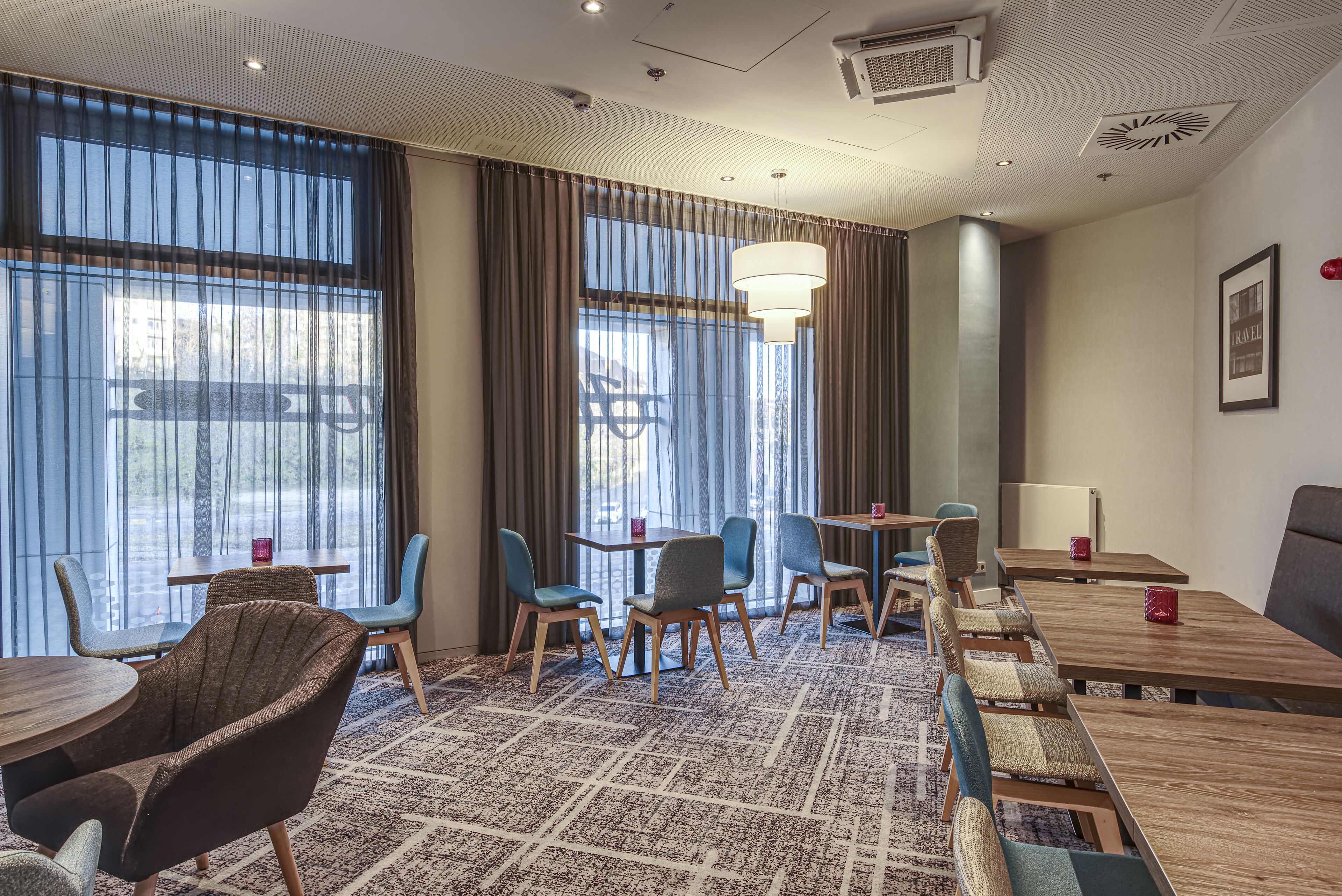 Ein Hotelzimmer mit großen Fenstern, Teppichboden und moderner Einrichtung.