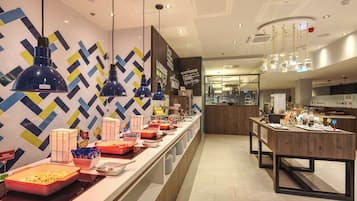 A modern hotel lobby with a buffet area featuring various food items and a decorative wall with geometric patterns.