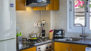 Eine Küche mit Holzschränken, einem Herd, einem Toaster und einem Fenster mit Blick auf Blumen.
