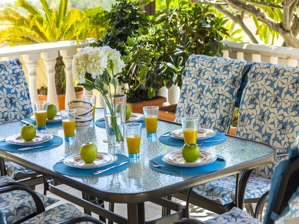 A dining table set with plates, glasses, and cutlery, surrounded by blue patterned chairs.
