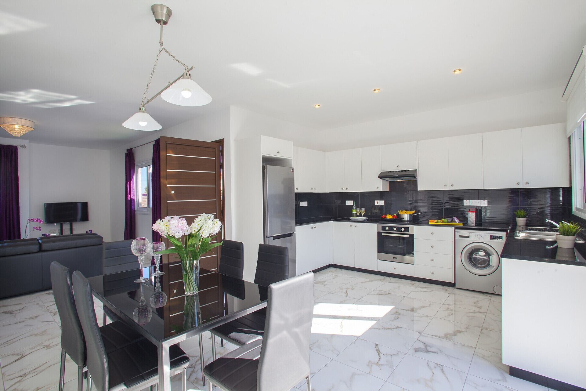 A modern kitchen with white cabinets, a black countertop, and stainless steel appliances.