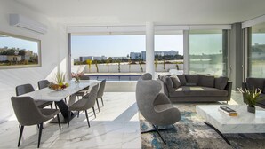 Ein modernes Wohnzimmer mit Blick auf einen Pool, einem Essbereich und einem großen Fenster.