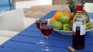 Ein Tisch mit einer Weinflasche, zwei Rotweingläsern, einer Obstschale und einer Ananas.
