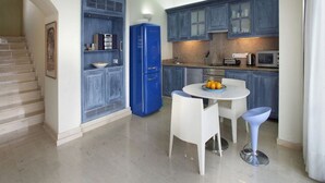Eine moderne Küche mit blauen Schränken, einem blauen Kühlschrank und einem Essbereich mit einem weißen Tisch und zwei weißen Stühlen.