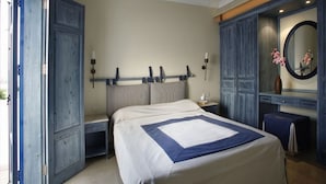 Ein Schlafzimmer mit einem Bett, einem Nachttisch, einer Kommode, einem Spiegel und einer Tür.