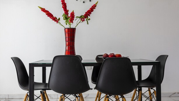 A dining table with a red vase and red flowers, black chairs, and a clock on the wall. - Your Dream 5-star Escape: Protaras Villa 1483 (Paralimni)