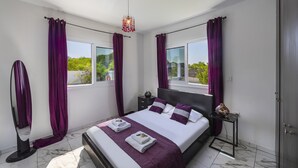 A modern bedroom with a large bed, two windows with purple curtains, a marble floor, and a pendant light. - Your Dream 5-star Escape: Protaras Villa 1483 (Paralimni)
