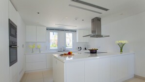 Eine moderne Küche mit weißen Schränken, einer zentralen Kochinsel und einem Fenster für natürliches Licht.