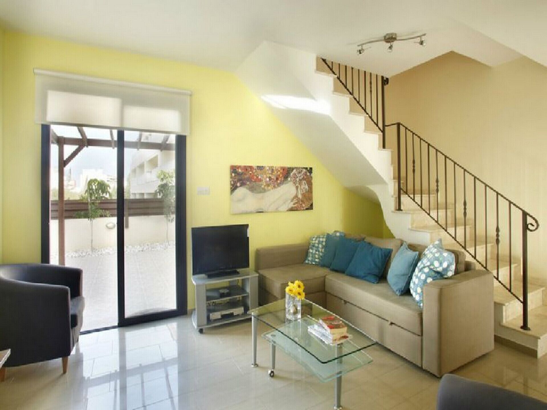 Una sala de estar con sofá, mesa de centro, televisor y escalera.
