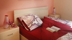 Ein Schlafzimmer mit einem Bett, einem Nachttisch, einer Vase mit Blumen und zwei gerahmten Bildern an der Wand.