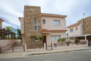 A modern two-story house with a stone facade, a flat roof, and a gated entrance. - The Ultimate Guide to Renting Your Luxury 3 Bedroom Villa With Private Pool, Protaras Villa 1452 (Paralimni)