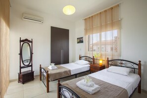 A hotel room with two beds, a wooden wardrobe, a mirror, and a window with curtains. - The Ultimate Guide to Renting Your Luxury 3 Bedroom Villa With Private Pool, Protaras Villa 1452 (Paralimni)
